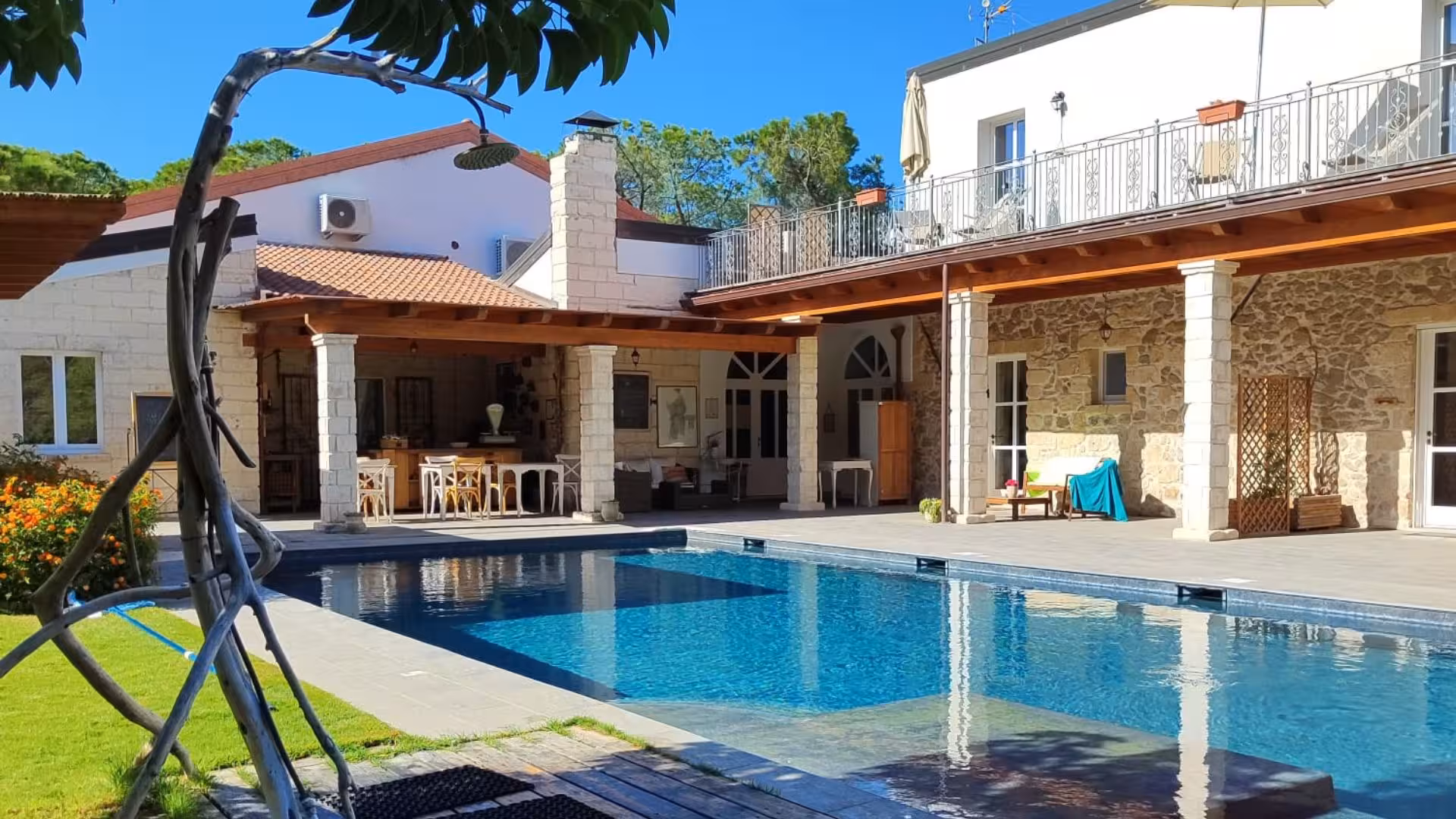 Charming villa with a serene poolside, surrounded by greenery and rustic architecture for a tranquil retreat.