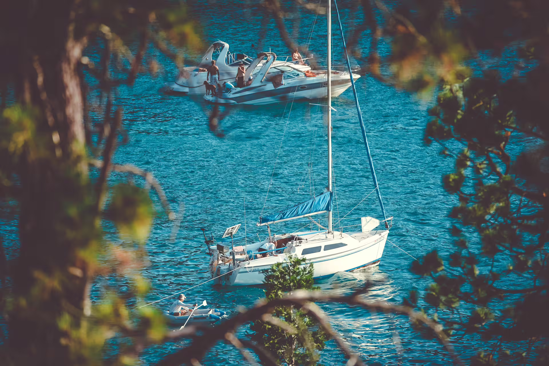 Two boats anchored in serene blue waters surrounded by lush greenery in Sotogrande, ideal for group charters.