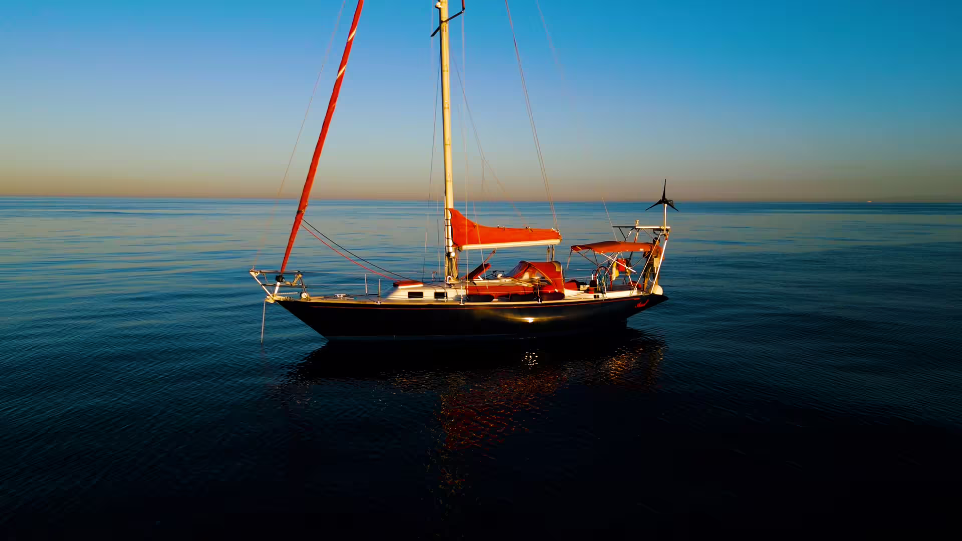 Sailboat with red sails gliding on calm waters during a Sotogrande private boat charter experience.