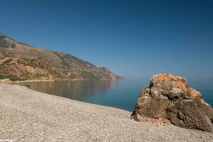 Tranquil Sougia Beach with clear blue waters and mountainous backdrop, perfect for a serene coastal escape.