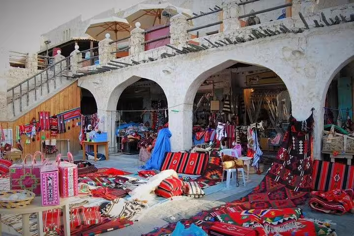 Colorful textiles and traditional goods at Souq Waqif market, showcasing Qatari culture during Doha transit tour.