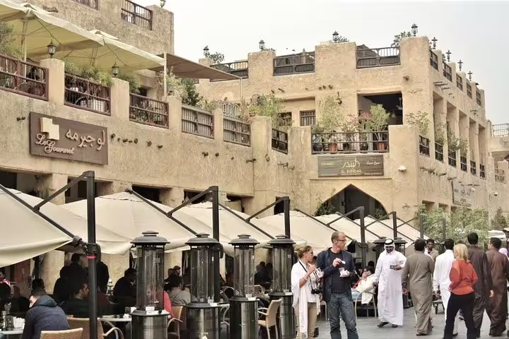 Bustling Souq Waqif in Doha with traditional architecture, outdoor cafes, and visitors enjoying the vibrant atmosphere.