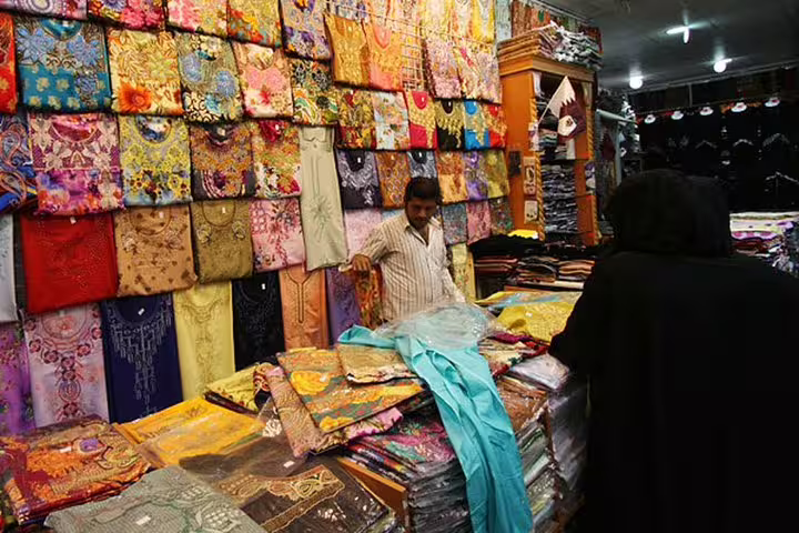Colorful fabric market in Doha's Souq Waqif, showcasing vibrant textiles during a Hamad Airport transit city tour.