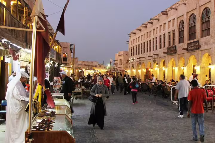 Bustling Souq Waqif at night in Doha, Qatar, with people enjoying the vibrant market atmosphere and local cuisine.