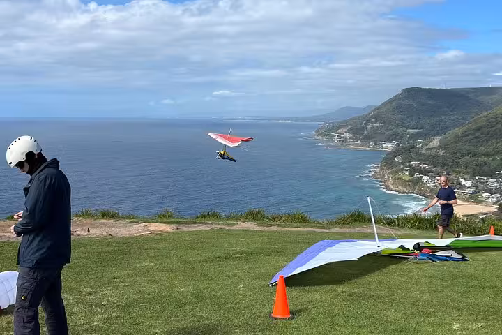 Hang gliders preparing for flight over scenic coastal cliffs with ocean views on the South Coast tour.