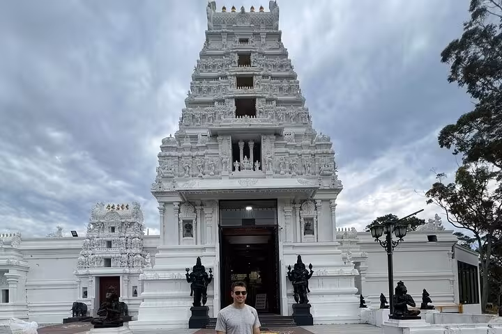 Traveler stands before a stunning white temple with intricate carvings, a highlight of the South Coast Private Daily Group Tour.