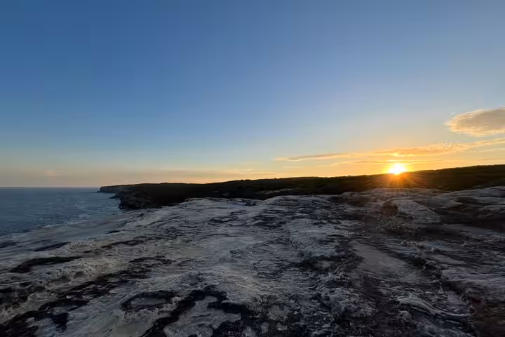 Stunning South Coast sunset over rugged cliffs, a highlight of the private daily group tour experience.