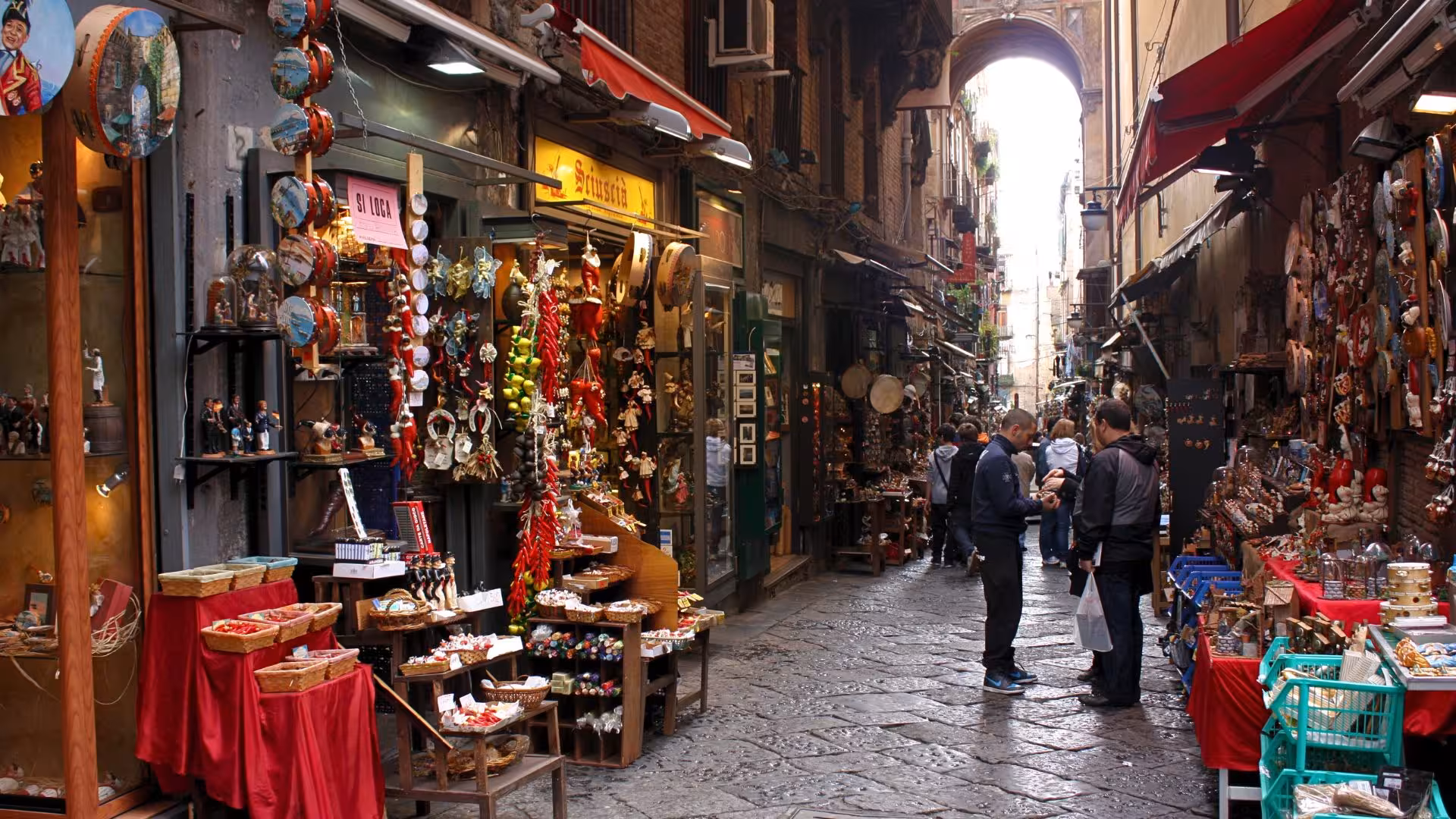 Quaint alleyway in Spaccanapoli lined with vibrant shops offering traditional crafts and souvenirs.