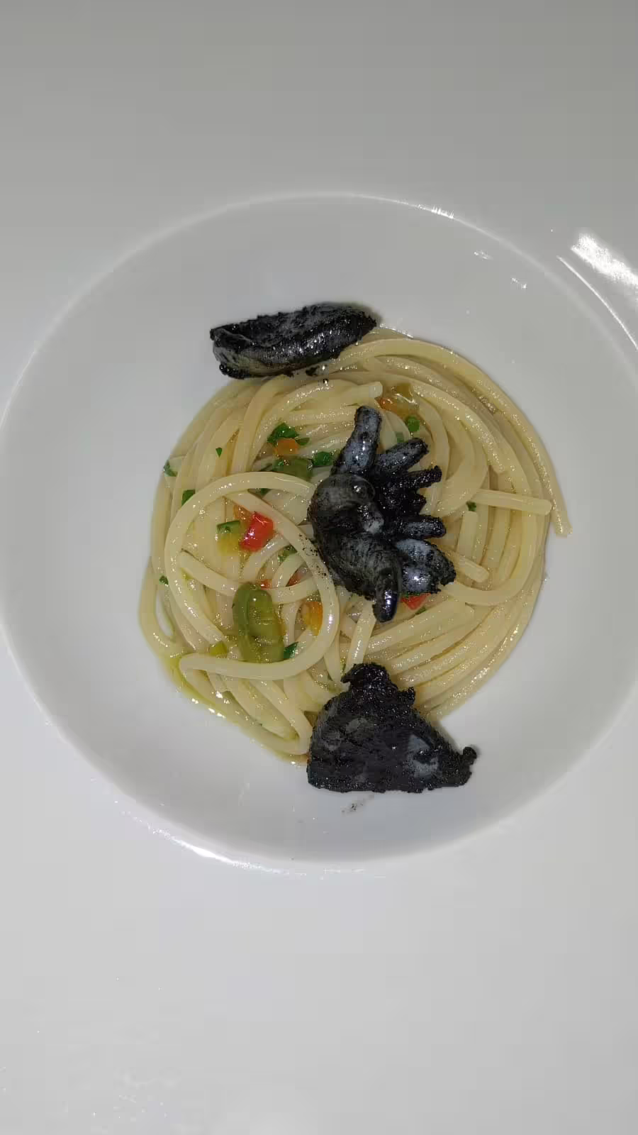 Spaghetti with squid ink seafood and fresh herbs, plated for a home dining experience at chef Angelo Lanaro’s restaurant