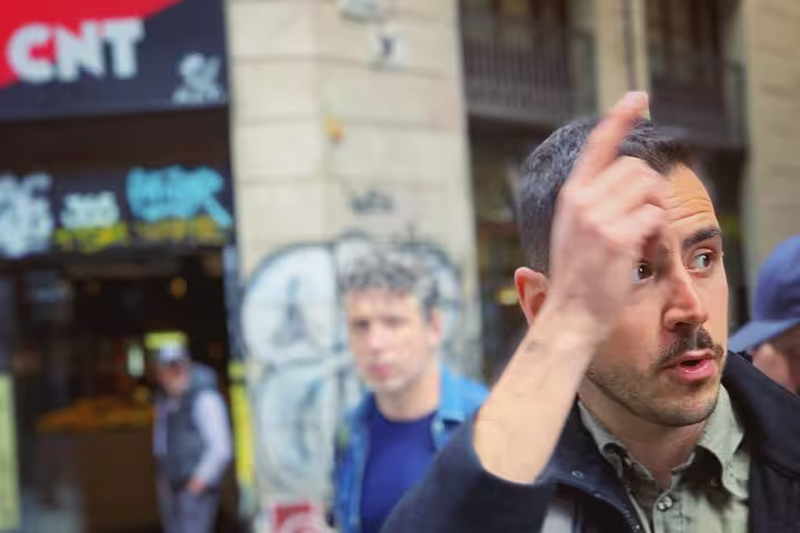 Tour guide explaining the history of CNT during the Spanish Civil War in a graffiti-adorned Barcelona street.
