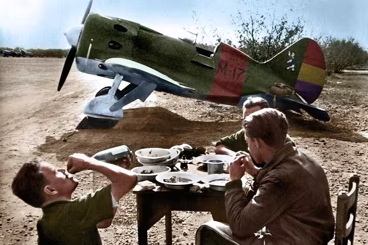Pilots dining beside a Republican biplane, showcasing the daily life of aviators during the Spanish Civil War.
