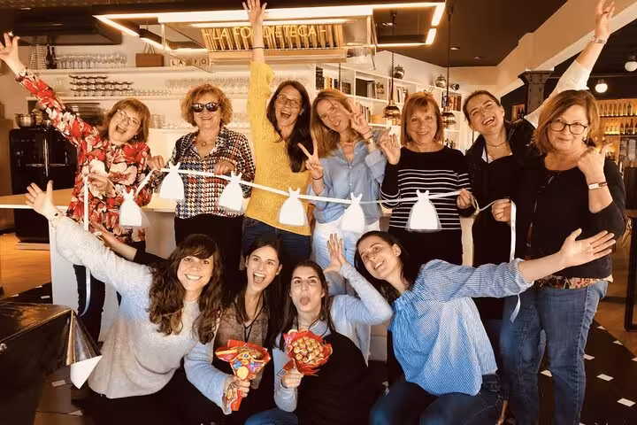 Happy group posing with decorations in a designer loft after a fun Spanish cooking class experience.