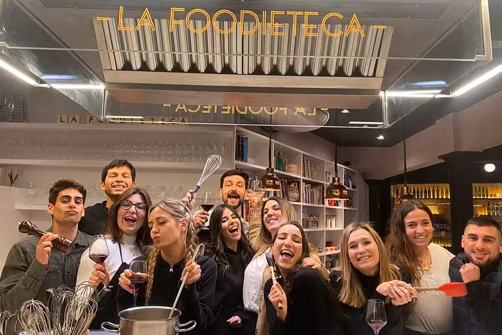 Group enjoying a Spanish cooking class in a stylish loft, holding wine glasses and utensils at La Foodieteca.