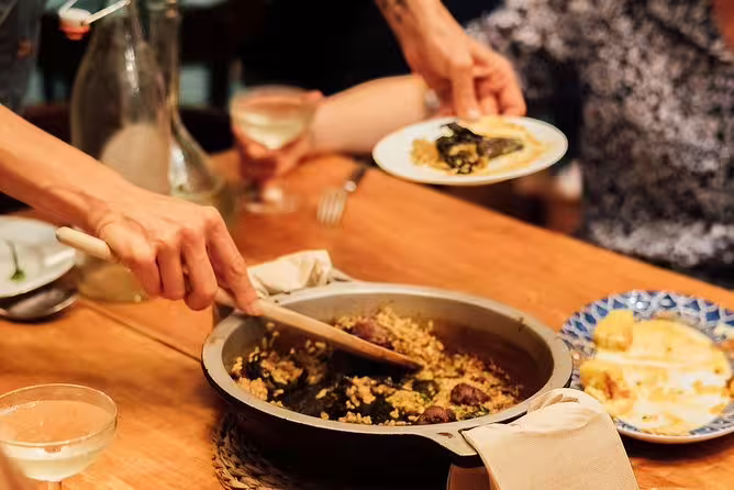 Hands serving traditional Spanish paella during a tapas and wine tasting event, creating an authentic culinary experience.