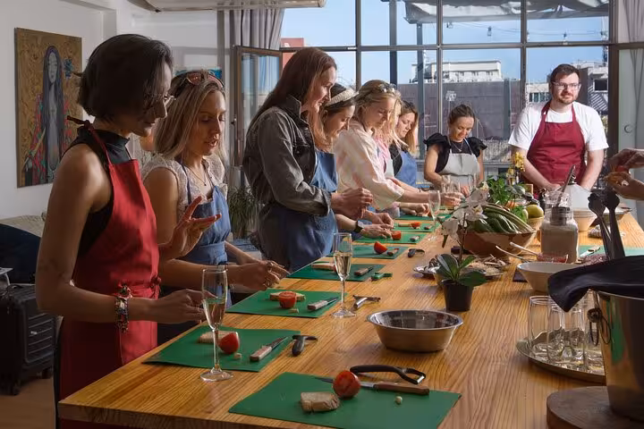 Group of women learning to cook Spanish tapas in a sunlit kitchen during a class in Barcelona.