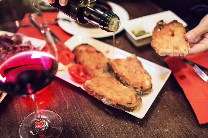 Spanish tapas with tomato bread and olive oil, paired with a glass of red wine for a culinary experience.