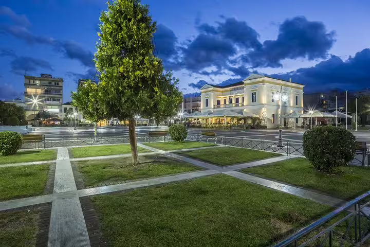 Evening view of Sparta city square with neoclassical buildings and gardens, highlight of a Sparta full day tour