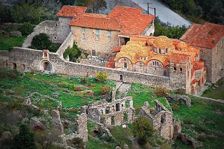 Byzantine monastery with orange domes and nearby ruins in Mystras, highlight of a Sparta full day tour