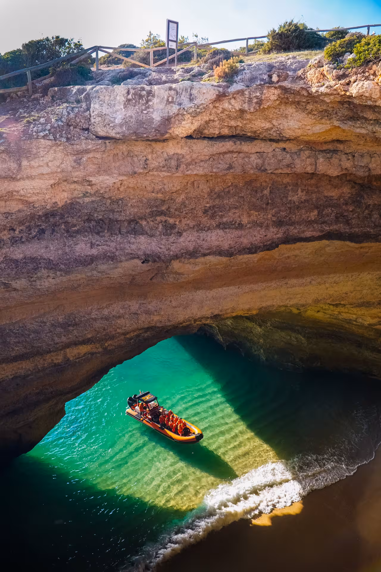 Aerial view of a speed boat entering iconic Benagil Cave with turquoise waters and golden limestone cliffs Algarve