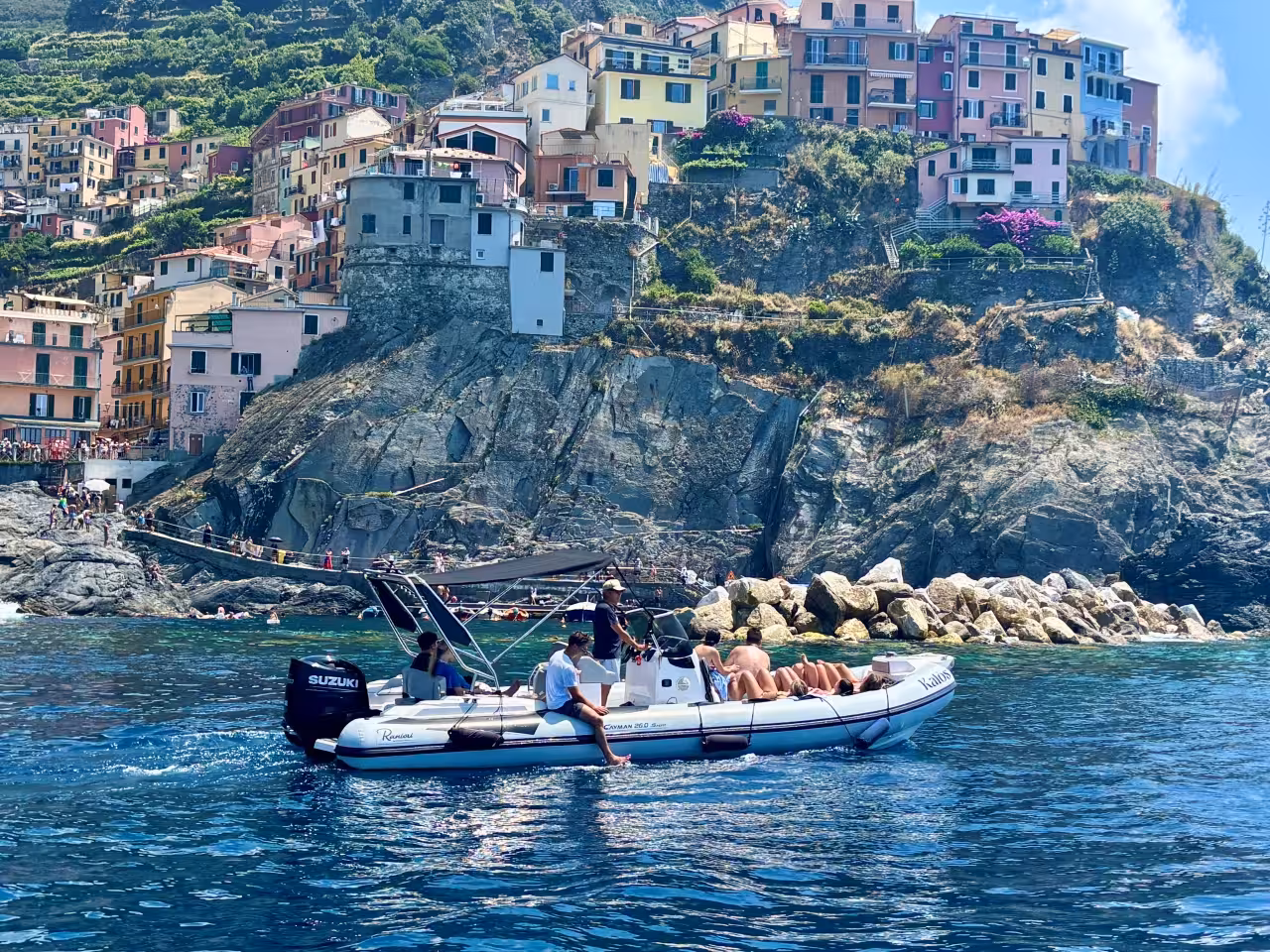 Speedboat cruising past Manarola on a La Spezia Cinque Terre full-day boat tour, cliffs and pastel houses