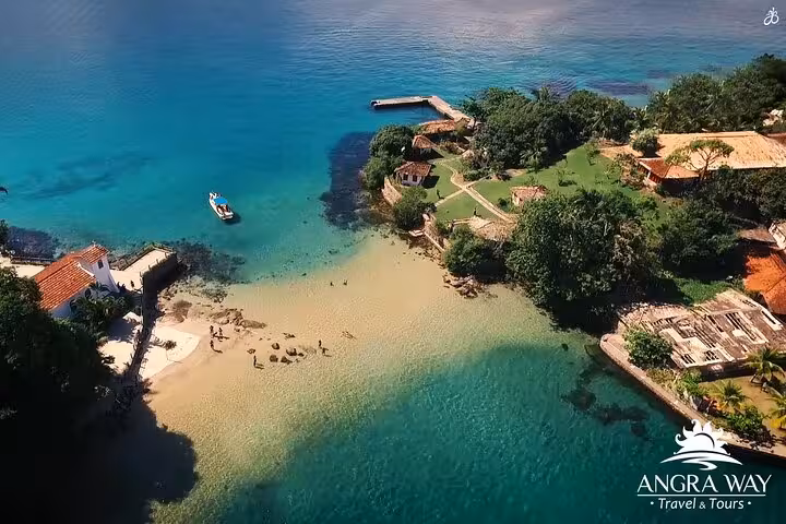 Aerial view of a speedboat approaching lush Paradise Island with clear turquoise waters and sandy beaches.