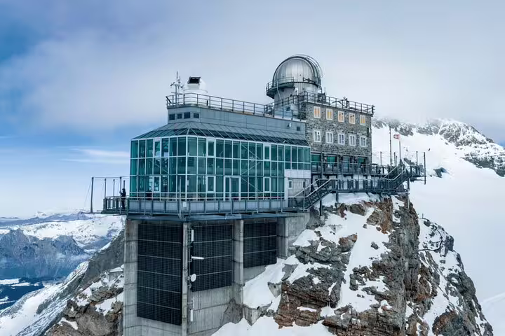 Panoramic view of the Sphinx Observatory at Jungfraujoch, perched on a snowy peak with stunning alpine scenery.