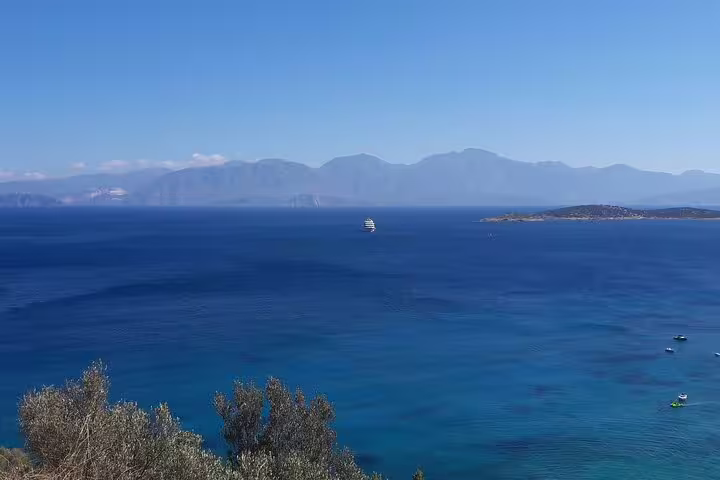 Expansive view of the deep blue sea with a distant cruise ship and mountainous backdrop near Spinalonga.