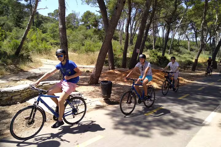 Cyclists on Split City Bike Tour riding a shaded pine forest path, guided bike excursion near Split