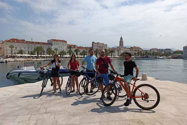 Cyclists on Split city bike tour at Riva waterfront promenade with Diocletian’s Palace skyline behind