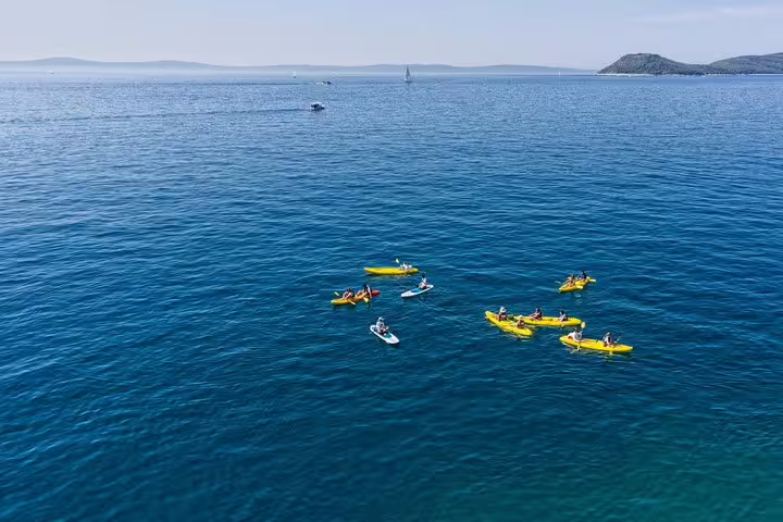 Drone view of group sea kayaking on open Adriatic from Split, ideal for guided snorkeling and island hopping