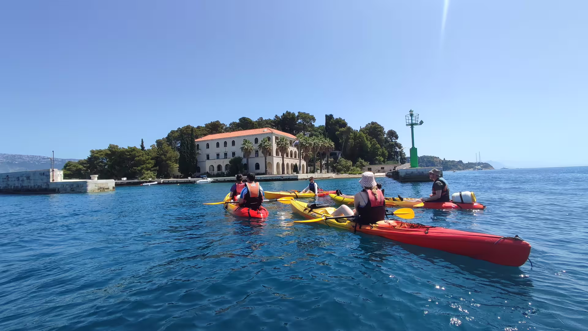 Guided sea kayaking group near Split harbor lighthouse, paddling calm Adriatic waters before snorkeling stop