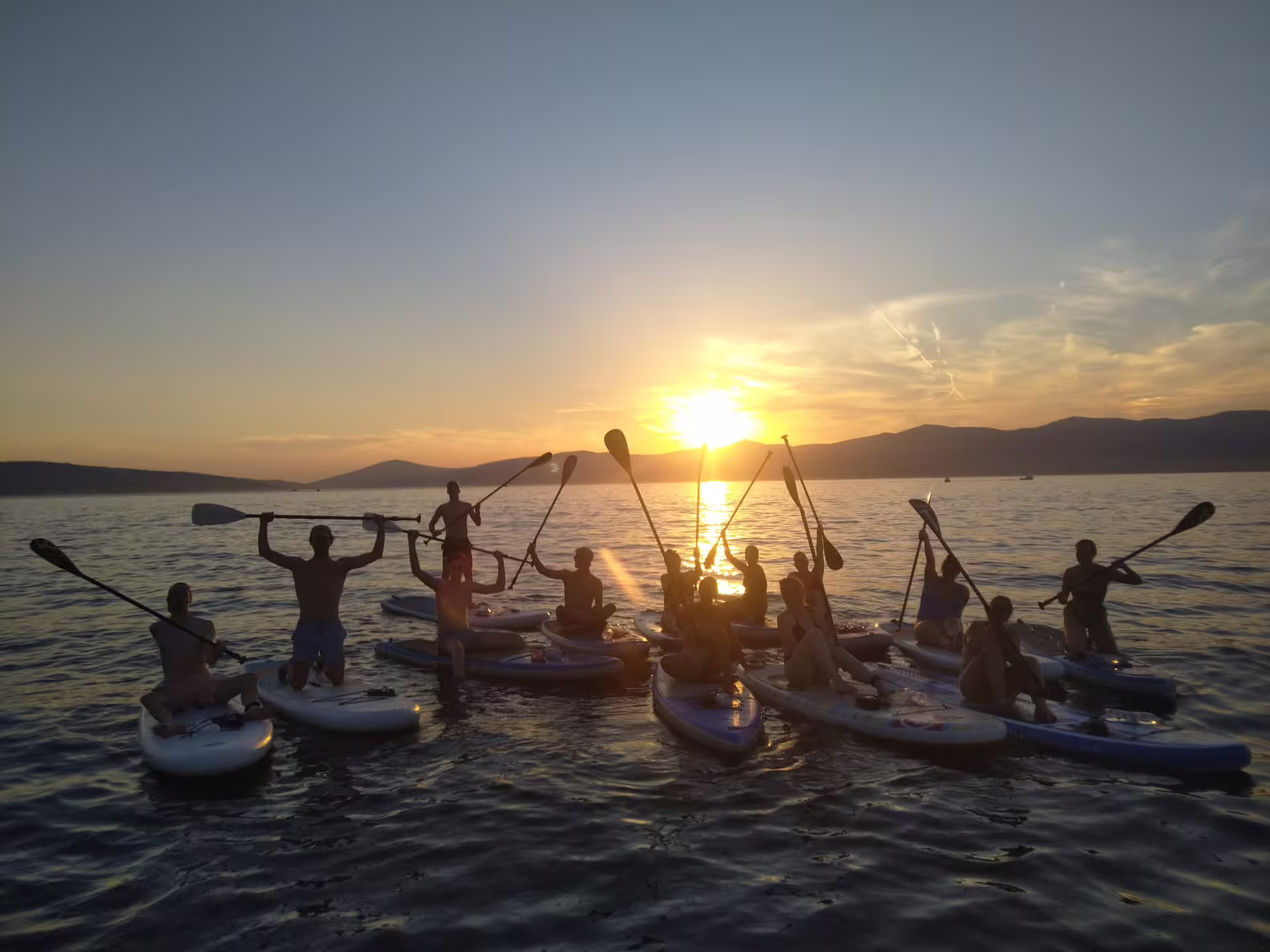 Group celebrates on boards during a Split sunset stand up paddle tour on the Adriatic Sea, ending with wine