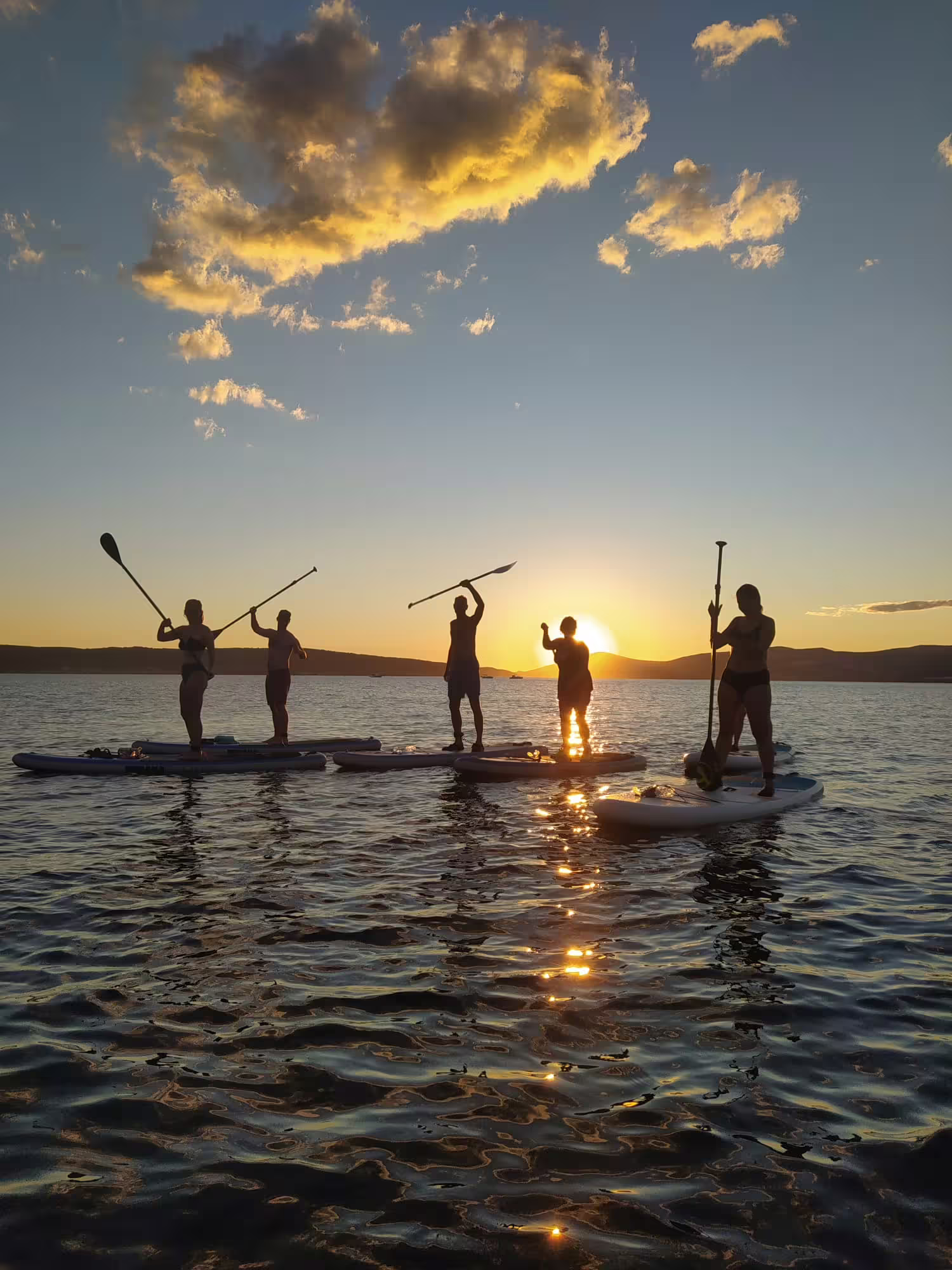 Group stand up paddleboarding at sunset near Split, Croatia, on a guided SUP tour with wine on the Adriatic