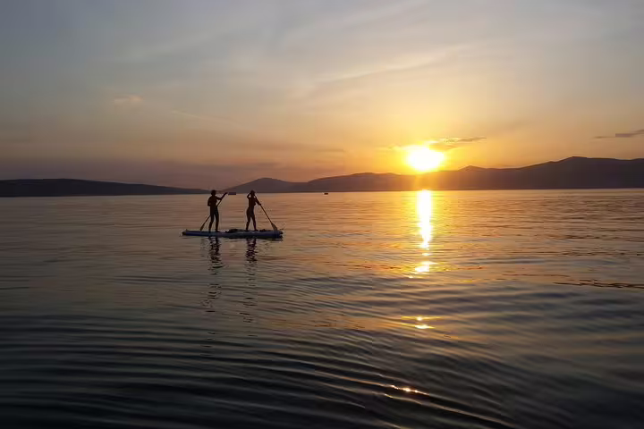 Couple stand up paddleboarding at sunset off Split, Croatia, with calm Adriatic views on a wine SUP tour