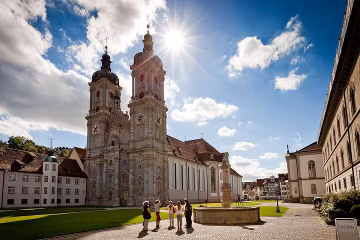 Stunning view of St. Gallen Cathedral under a bright sky, showcasing its baroque towers and lush grounds.