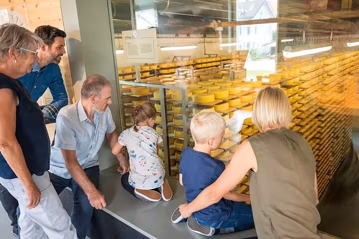 Visitors admire cheese wheels at a St. Gallen dairy, part of the cultural and culinary tour experience.