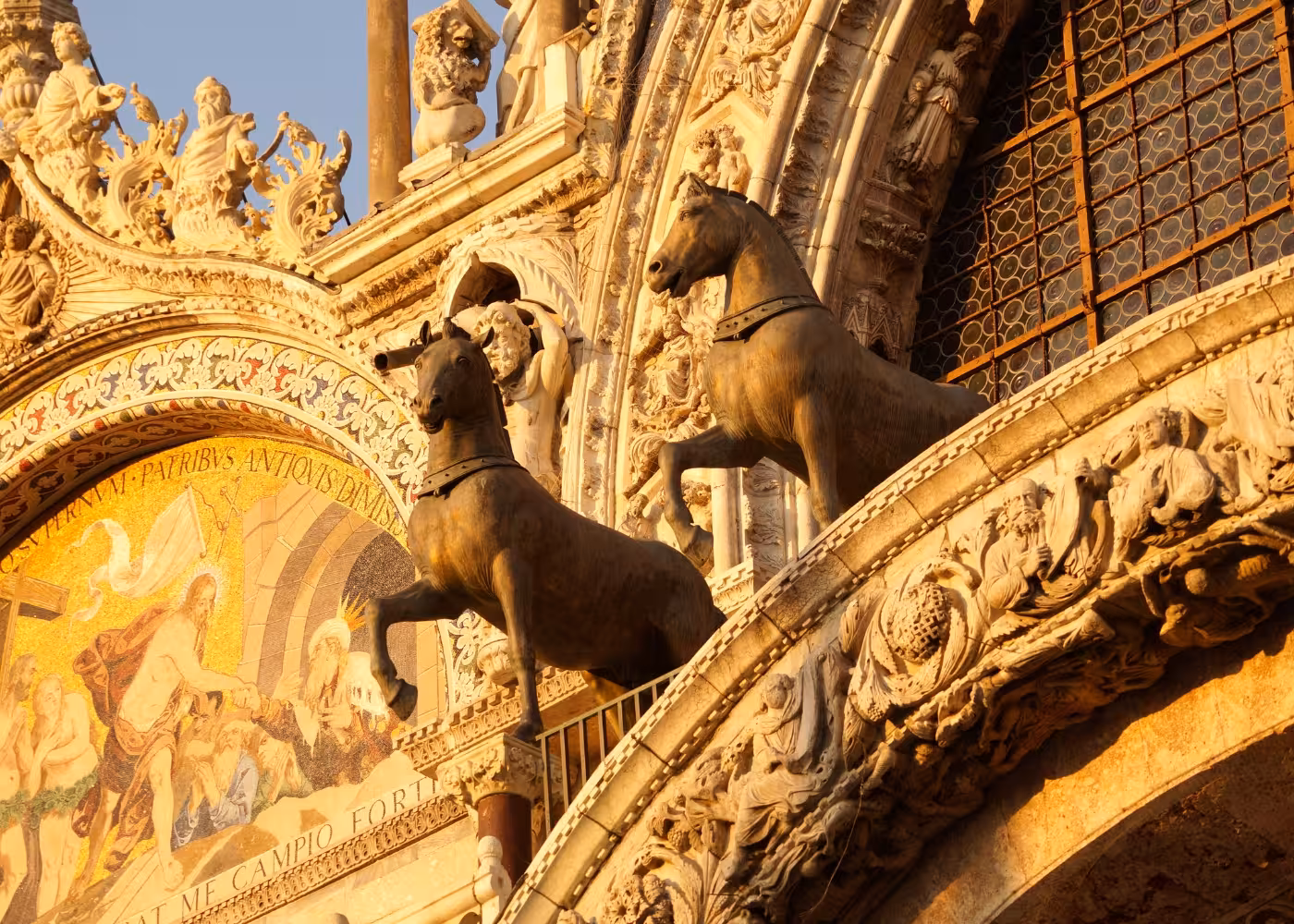 Bronze horses and detailed mosaics on the facade of St Mark's Basilica, showcasing Venice's rich architectural heritage.