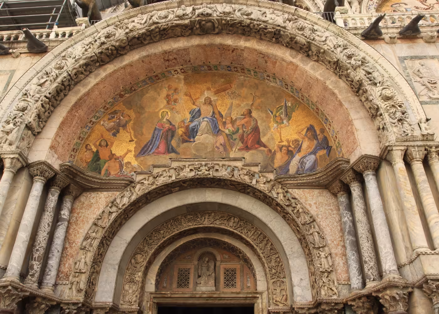 Exterior of St. Mark's Basilica with detailed mosaics and ornate arches, highlighting Venice's architectural grandeur.
