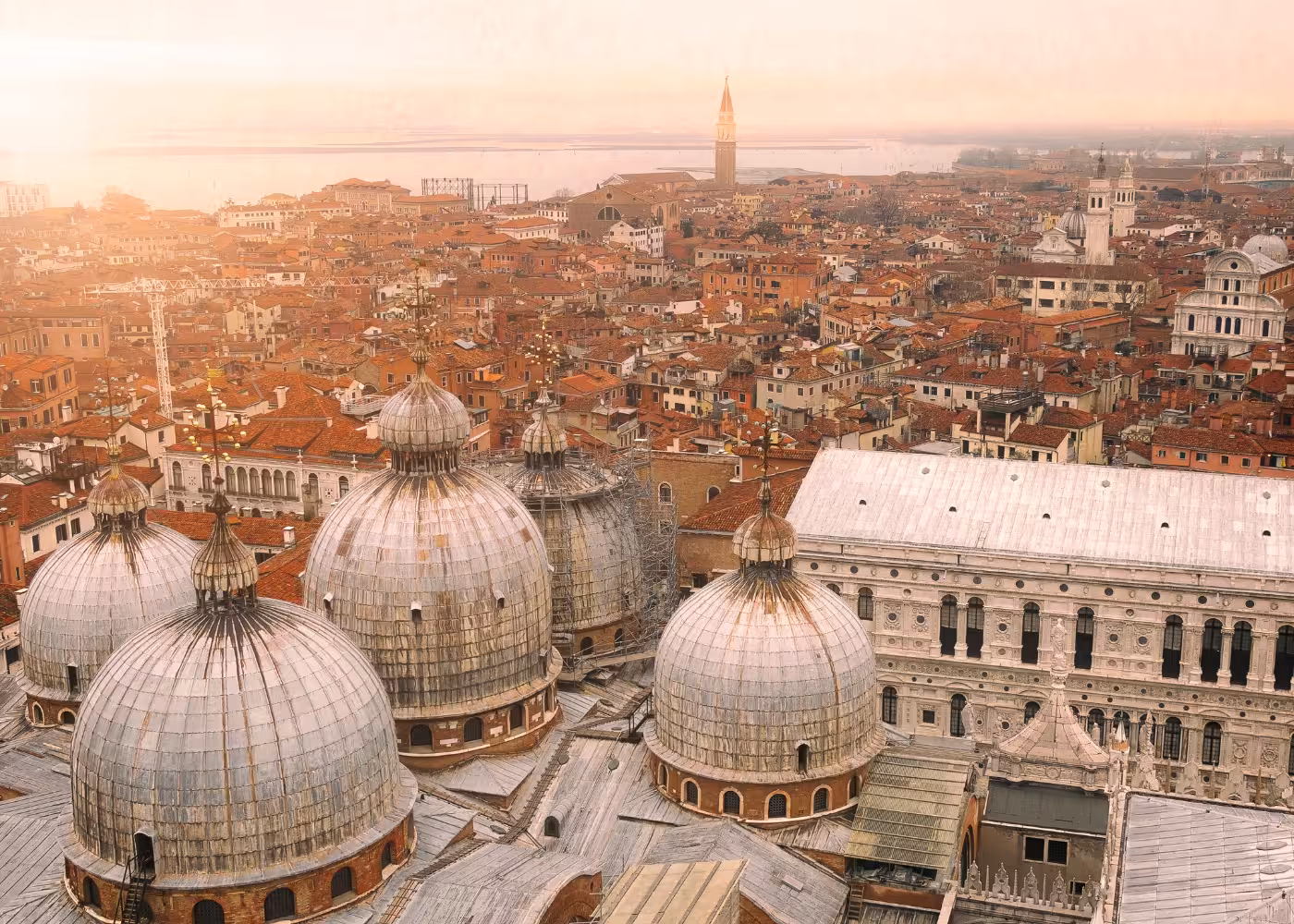 Aerial view of Venice's skyline showcasing the domes of St. Mark's Basilica and the historic city's unique architecture.