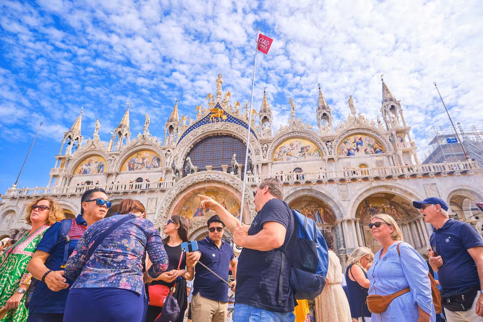 Tourists gather outside the stunning St. Mark's Basilica in Venice, highlighting its ornate architecture and vibrant mosaics.