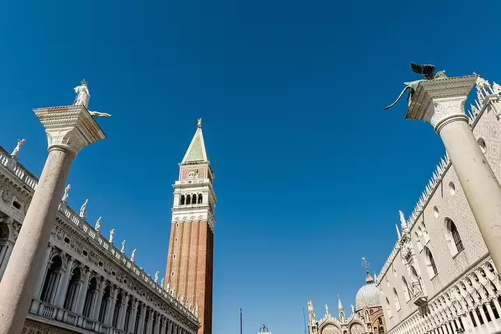 View of St Mark's Campanile and surrounding columns under a clear blue sky, iconic sights on a luxury Venice tour.
