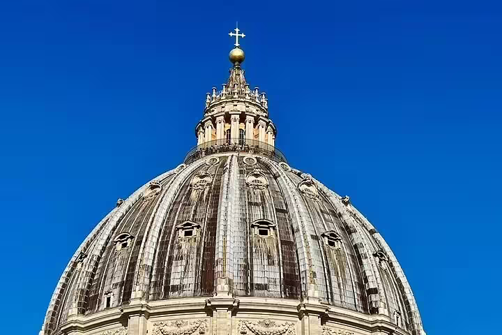 Close-up of St Peter’s Basilica dome against a clear blue Rome sky, highlighting details seen on the VIP early morning climb tour