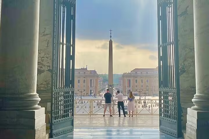 Guests on an early morning VIP St Peter’s Basilica dome tour admire St Peter’s Square and Vatican obelisk from grand open doors