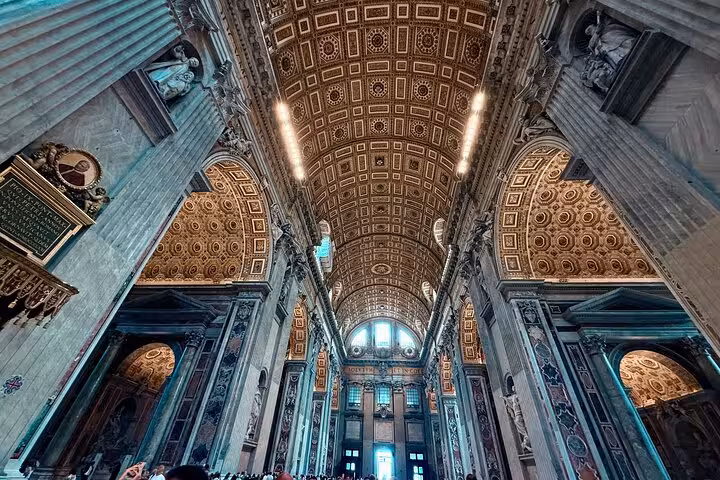 Magnificent interior view of St Peter's Basilica showcasing intricate ceiling details on a small group private tour.