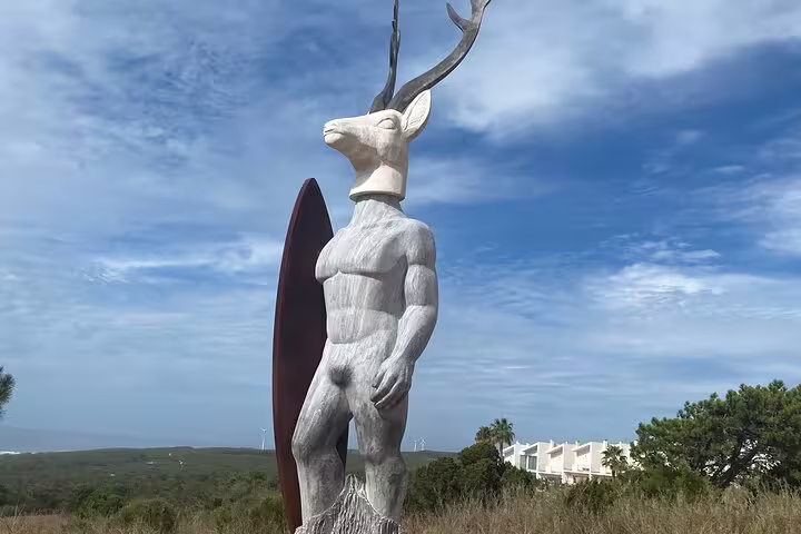 Unique stag-headed statue with surfboard in Nazaré, Portugal, symbolizing the blend of nature and surf culture.