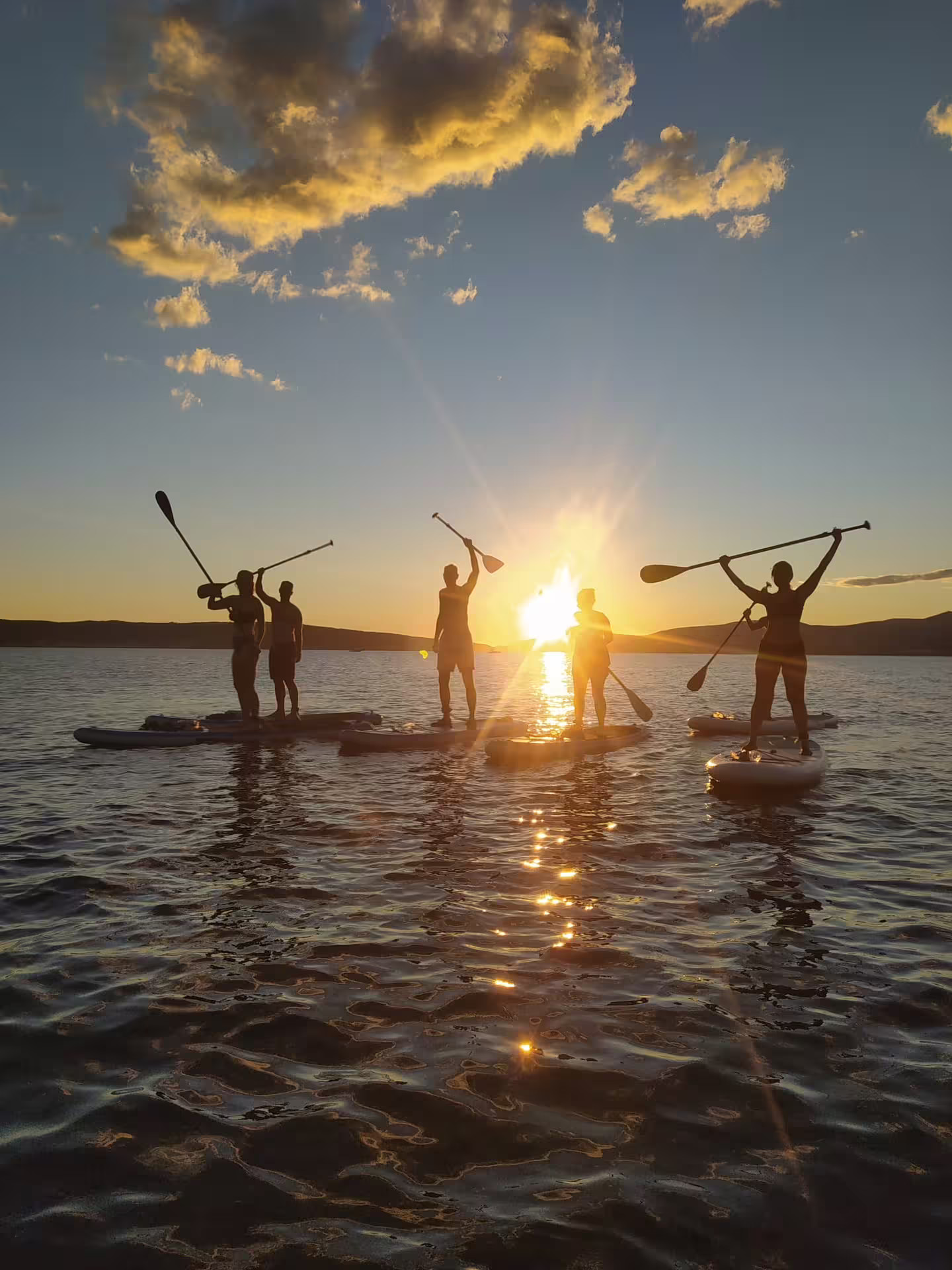 Group on a stand up paddle tour in Split at sunset, paddling on the Adriatic Sea with golden reflections
