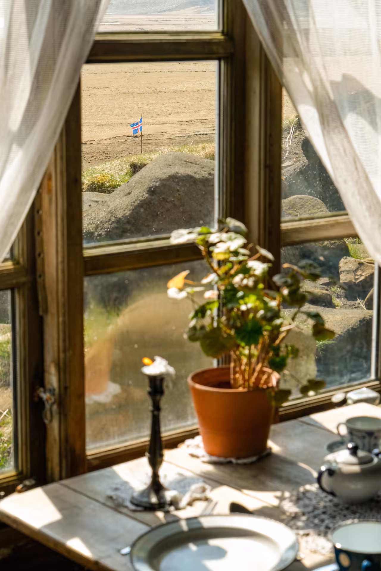 Rustic cave window view featuring a potted plant and Icelandic flag, highlighting the standard cave tour atmosphere.