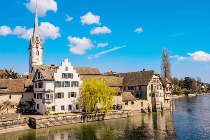 Scenic view of Stein am Rhein with a church spire and charming riverside houses under a bright blue sky.