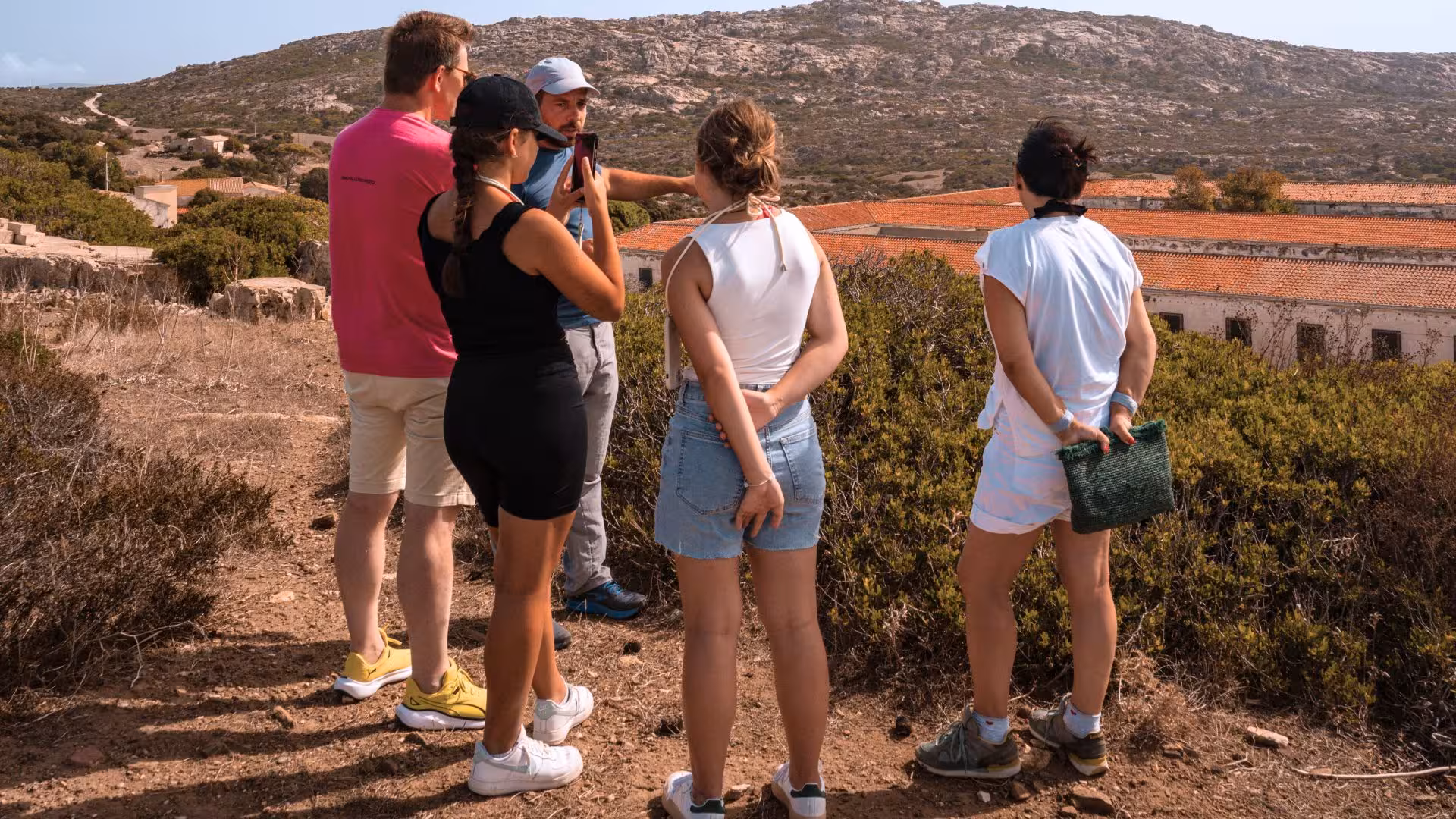 A guide shares insights with a group of tourists overlooking Asinara's scenic terrain during a Stintino tour.