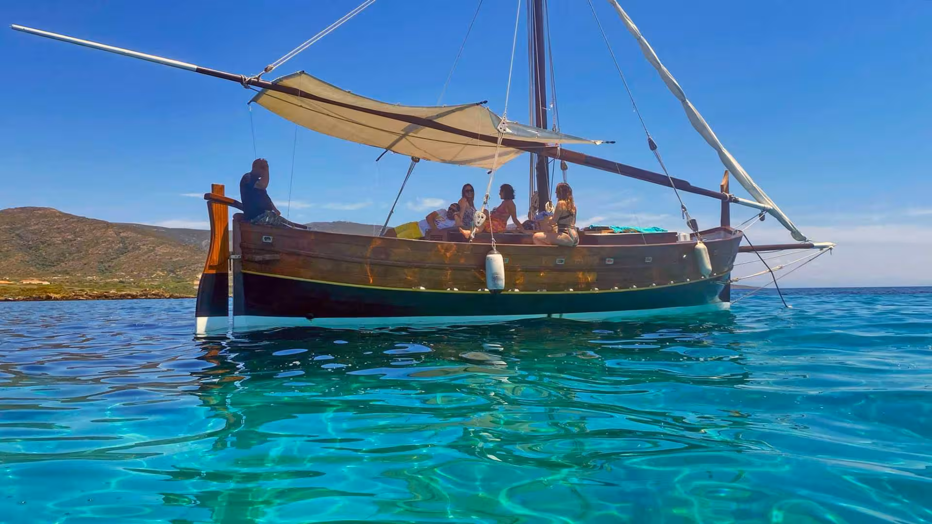 Tourists relax on a traditional sailboat under a sunny sky, enjoying a scenic Stintino to Asinara sailing trip.